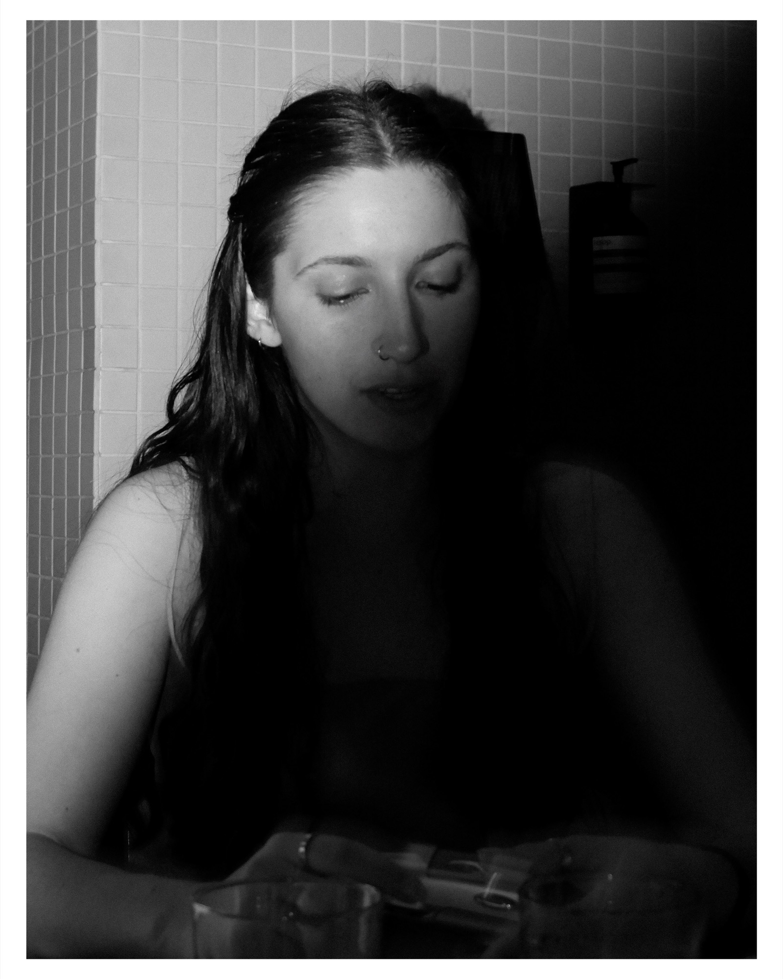 Woman in a tiled bathroom, soft light, black and white portrait